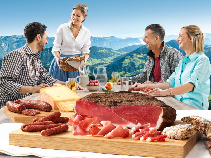 Nichts für Vegetarier: fleischliche Genüsse vor Alpenpanorama. (Handl Tyrol)