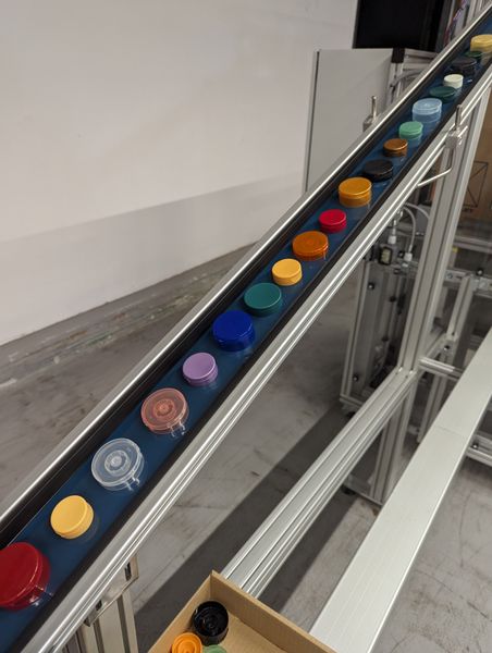 Für die Automatisierung von Montage- und Verpackungsprozessen nutzt KM Packaging zahlreiche Item-Komponenten. So setzt das Unternehmen Gurtförderer ein, um einzelne Komponenten zu Montage- und Veredelungsmaschinen sowie fertige Verschlüsse zu einer Befüllstation zu transportieren. (Bild: Item / KM Packaging)