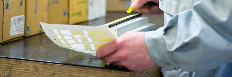 Schaltschrankbau bei Schubs: Ein Elektriker beschriftet einen Sicherungskasten.(Bild:  Thorsten Sienk/Schubs GmbH)