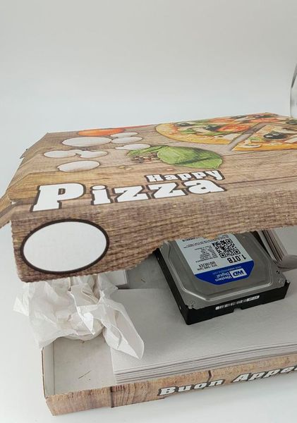 Einmal Festplatte Capricciosa zum Mitnehmen! Auf der Attingo-Homepage finden sich detaillierte und sogar anschaulich illustrierte Anleitungen zum Verpacken eines defekten Datenträgers. Es ist natürlich verständlich, dass nicht jeder immer sofort die passenden Materialien zur Hand hat, um diese Anweisungen hundertprozentig zu befolgen. Was sich der Kunde in diesem Fall ausgedacht hat, fällt jedoch nicht einmal mehr unter „behelfsmäßig“: neben normalen Paketen hatte der Paketzusteller eines Tages auch einen Pizzakarton in der Hand. Die Freude der hungrigen Mitarbeiter über diesen unverhofften Snack war jedoch von kurzer Dauer. Der Karton war sorgfältig zugeklebt und frankiert worden. Im Inneren befand sich eine defekte externe Festplatte, die nur mit losen Papierhandtüchern „gesichert“ worden war. Der Kunde hatte jedoch Glück im Unglück – die Platte hatte trotz der unsachgemäßen Verpackung keine weiteren Schäden erlitten und die Daten konnten gerettet werden!  (Bild: Attingo)