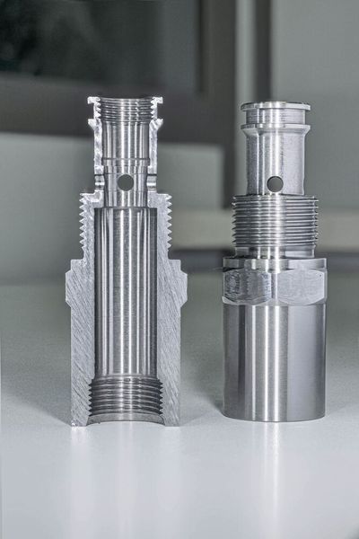 The component on the right and the cut-open version for examination on the left. The complete bore and the two cut-open bores on the left and right (in the left component) are clearly visible. The bore diameter is 5 mm, the inner diameter of the main bore at this point is 14 mm. The hole exit on the inside of the workpiece shown in the close-up (Fig. 3) was produced after approximately 4,000 drillings with the ExBurrDrill. There is no visible burr. (Image:Kempf GmbH)