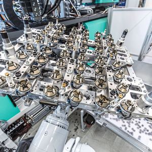 Der KR Quantec, der maximale Wiederholgenauigkeit und kontinuierliche Präzision erreicht, hat Zugriff auf die Spritzgussmaschine. Er entnimmt simultan zum Spritzzyklus die Rollen aus ihrem unteren Teil und setzt sie in die Steckbuchsen ein, um die fertigen Teile aus Kunststoff danach zu entnehmen und auf dem Förderband abzulegen.(Bild:  Kuka Group)