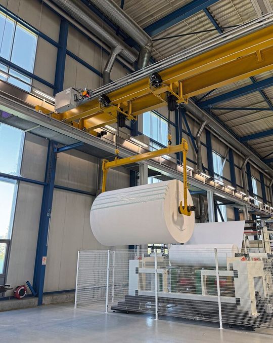 Zwei parallel arbeitende, elektronisch überwachte Kettenzüge heben, transportieren und positionieren bis 1600 kg schwere Papierrollen.(Bild:  GIS)