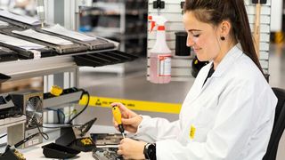 Nur mit entsprechender Ausrüstung sollte man sich an ESD-Arbeitsplätze begeben: Hier ist eine Mitarbeiterin mit ESD-Kittel und ESD-Armband an einem ESD-Arbeitstisch zu sehen.  (Bild: item Industrietechnik GmbH)