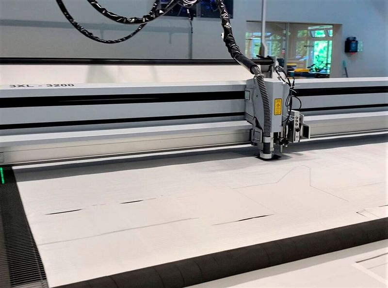 Blick auf den Laserschneidkopf einer 3XL-3200 von Eurolaser, wie er das robuste Polypropylen-Mischgewebe automatisch in Form bringt. Vorbei sind die Zeiten, in denen Mitarbeiter mühsam per Heißschere arbeiten mussten. (Bild: Eurolaser)