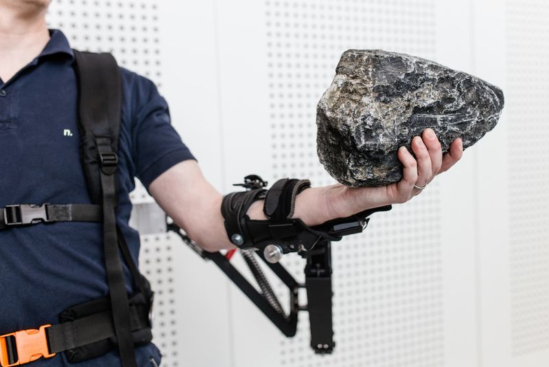 Dr. Konrad Stadler, Dozent für Regelungstechnik, Zürcher Hochschule für Angewandte Wissenschaften, demonstriert die Funktionsweise des Exoskeletts. Zu sehen ist die passive Unterstützung zum Heben schwerer Lasten. (Bild: Ludmilla Parsyak/Fraunhofer IAO)