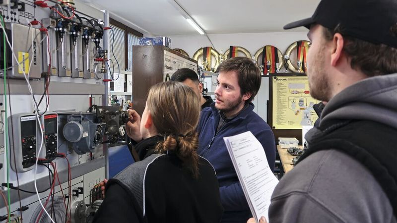Oldtimeraffine Lehrlinge der Kfz-Innung Region Stuttgart am Schulungsmodell des Gemischbildungssystems L-Jetronic(Bild:  Diehl – VCG)