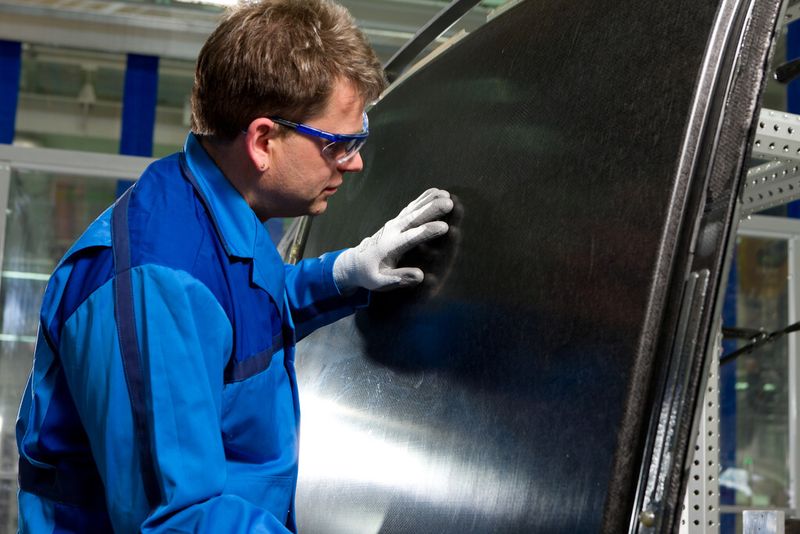Ein BMW-Mitarbeiter prüft die Qualität und Oberflächenbeschaffenheit eines gefertigten CFK-Karosseriedachs. (Bild: BMW)