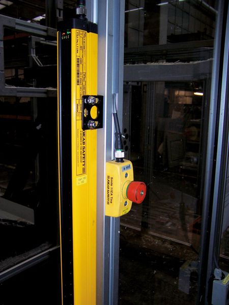 Bild 3: Dieser Unfallschutz-Lichtvorhang hat einen Querschnitt von nur 37 mm x 48 mm und eine Schutzfeldhöhe von 1500 mm. Dahinter ist ein Not-Halt-Taster mit M12-Stecker und LED-Anzeige. (Bild: ABB)