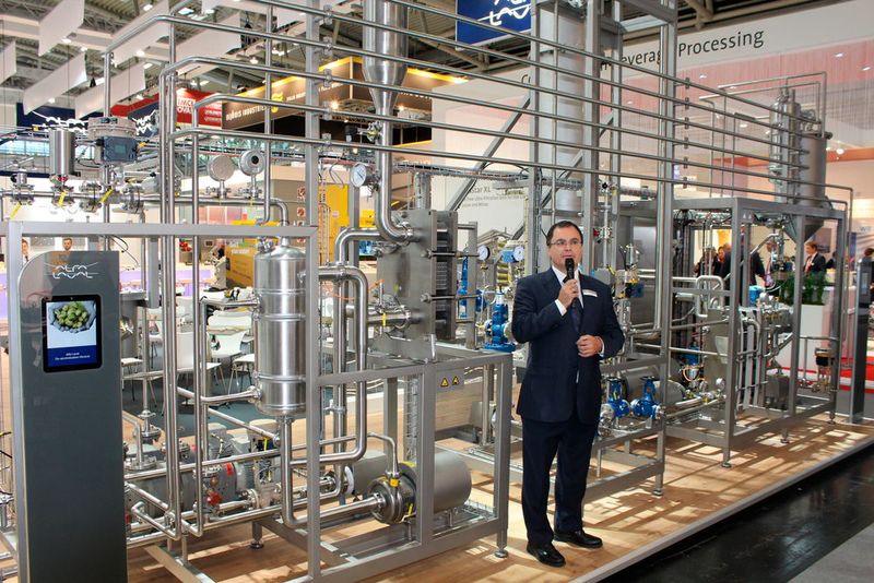 Besonders imposant und platzeinnehmend: ein Entalkoholisierungsmodul zur Herstellung von alkoholfreiem Bier mit weniger als 0,05 % Alkohol. Es entgast zuerst das Bier, bringt kondensierbare flüchtige Stoffe zurück in den Bierstrom und entfernt dann den Alkohol mit Reinstdampf, der nach oben in eine Strippingkolonne fließt. (Bild: Kempf/PROCESS)