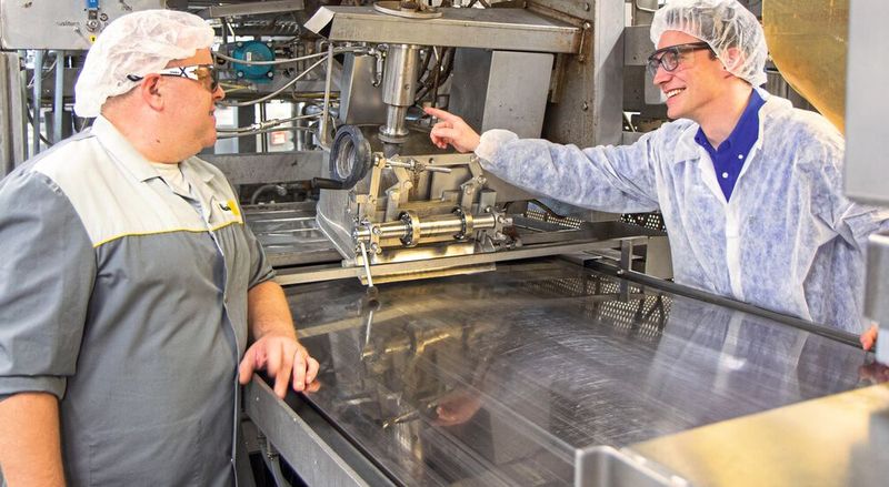 Gespräch zwischen Patrick Marquis und Thomas Flückiger bei der Produktionslinie. (Bild: Ricola)