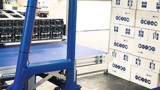 Über dem blauen Förderband zur weiteren Abfuhr der Pakete nach links ist der Vakuumgreifer mit den Scanner-Modulen zu erkennen. (Maienschein)