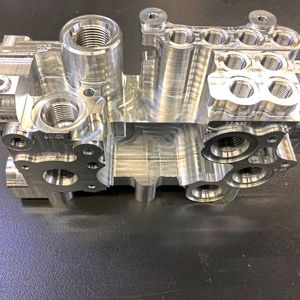 Ein individuell von Ekomat gefertigter Hydraulikblock. Deutlich zu erkennen sind die hauptsächlichen Bearbeitungsarten: Fräsen, Bohren, Gewinden.