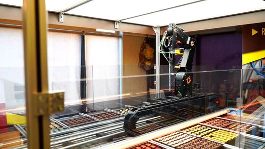 Der Chocomatic von Roose Automation ist ein echter Hingucker im Verkaufsbereich. Der Kunde steuert mit einem Tablet oder dem eigenen Smartphone einen Roboter, der aus einer Palette unterschiedlicher Pralinen individuell für den Kunden auswählt.(Bild:  Roose Automation)