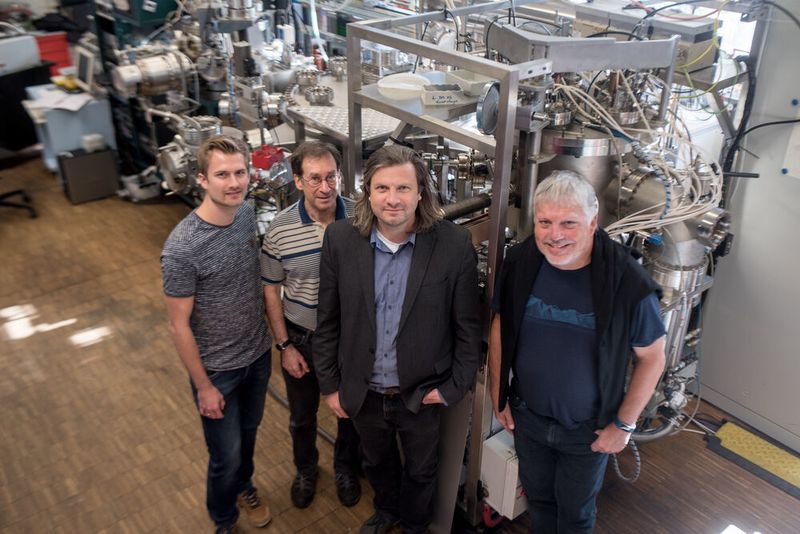 Das Forscherteam Tobias Löffler, Alan Savan, Alfred Ludwig und Wolfgang Schuhmann (von links) vor der kombinatorischen Sputteranlage, in der die Nanopartikelbibliotheken hergestellt wurden. (RUB, Kramer  )