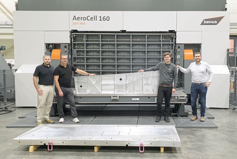 Präsentieren stolz das fertige Musterbauteil vor der «AeroCell 160 | 400» (von links): Jens Ilg (Business Development, Aerospace & Composites Mapal), Alexander Follenweider (Component Manager Aerospace & Composites Mapal), Stefan Diem (Anwendungstechniker Bavius) und Dominik Merz (Director Global Sales Bavius). Im Vordergrund die zur Aufspannung verwendete Vorrichtung. (Bild: Mapal)