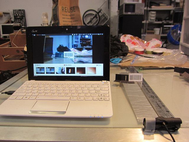 Look at a barcode through the webcam to refocus it to about 20 cm away. Use a webcam program like Photo Booth. A barcode has fine details so it's a nice test of focus. (The above image is of an older kit). Rotate the camera lens to adjust the focus. You may need to gently use a pair of needle-nosed pliers at first. Anything around 20 cm away from the lens should be in focus. This means your slit will be in focus when the box is closed. If you don't carefully refocus your camera, your spectra will be of very low resolution. Now snap your webcam back together. (PLOTS/CC BY 2.0)