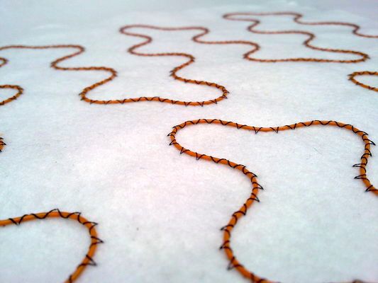 Längst ein Wärme-Klassiker: Solche isolierten Kupferdrähte für Auto-Sitzheizungen werden zumeist per Drahtlegetechnik auf Textilmaschinen befestigt. (Bild: Tajima)