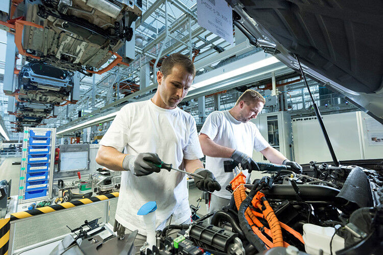Zwei Mitarbeiter im Audi-Werk in Ingolstadt montieren den Audi A3 Sportback e-tron. Aktuell arbeiten so genannte kollaborierende Roboter in ersten projekte mit Werkern zusammen – ohne Schutzzaun, Just-in-time und Just-in-Sequence gehören zum Standard. Mit vier Monatslöhnen lässt sich heute hingegen kaum ein neues Auto erwerben. (Foto: Audi)