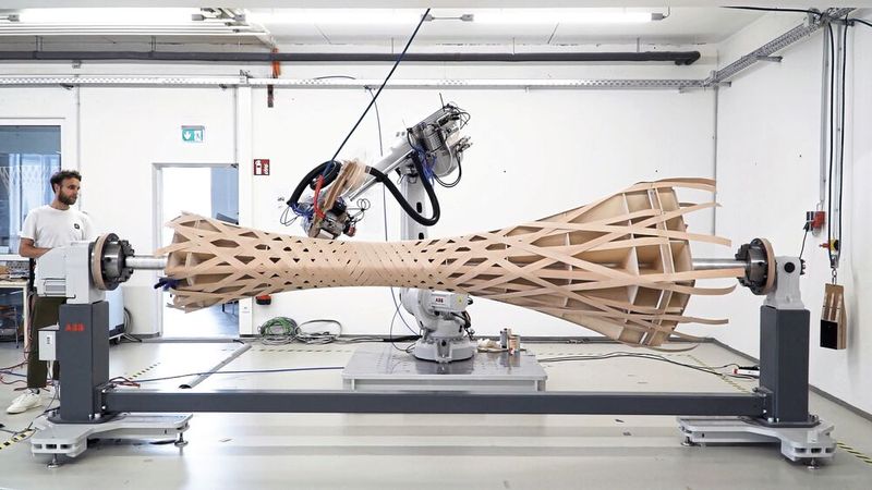 An der Universität Kassel haben Forschende ein Verfahren entwickelt, bei dem Deckenelemente und Stützpfeiler mit bis zu einem Meter Durchmesser und 3,5 Metern Länge aus gewickeltem Furnierholz hergestellt werden. Für die Entwicklung und Fertigung kommen Roboter von ABB zum Einsatz.(Bild:  EDEK/Universität Kassel)