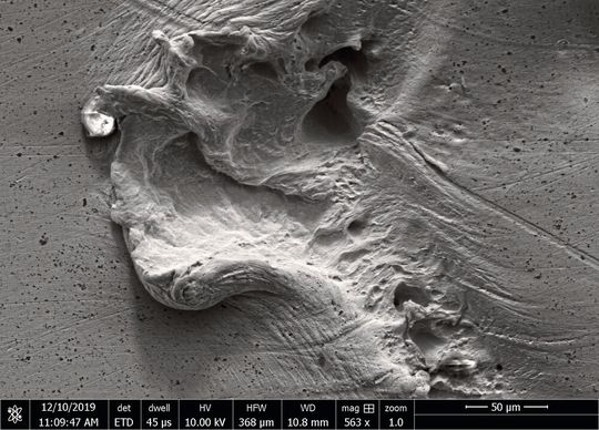 Elektronenmikroskopieaufnahme einer durch Kavitation in Wasser geschädigten Metalloberfläche aus Silber. Elektronenmikroskopieaufnahme einer durch Kavitation in Wasser geschädigten Metalloberfläche aus Silber.