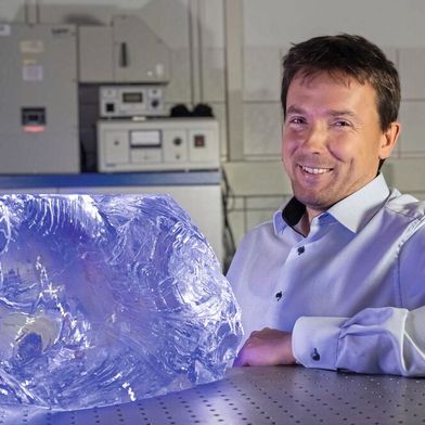 Prof. Lothar Wondraczek, Leiter des Otto-Schott-Instituts für Materialforschung, neben einem Glasblock bestehend aus hochreinem Borosilikatglas (Bild: Jens Meyer (Universität Jena))