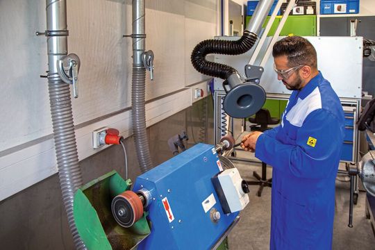 Die Fächerschleifmaschine ist via Schlauch und Rohrleitung an den Nassabscheider angeschlossen. Der Absaugarm kann bei größeren Staubmengen hinzugenommen werden.(Bild:  Esta)