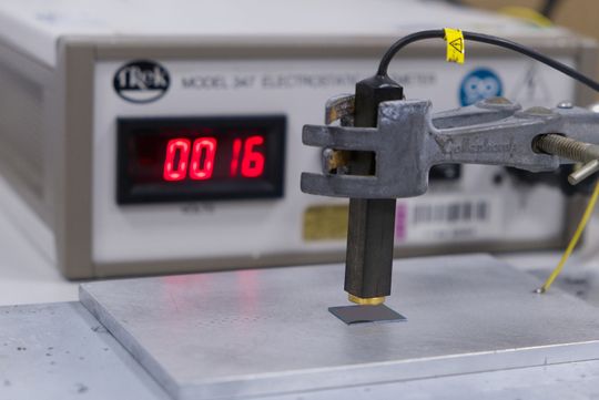 Die beschichtete Siliziumprobe auf einem Messgerät: Im Hintergrund zeigt das Gerät ein Oberflächenpotenzial von 16 Volt an.(Bild:  Christina Anders, Uni Kiel)
