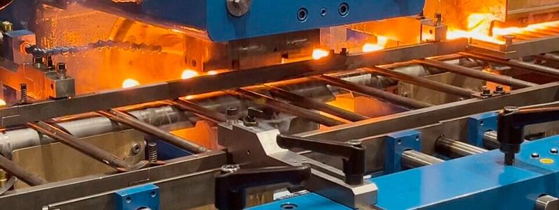 Schraubenkopfumformung mit Wärme: In der Induktionsstufe werden die Köpfe der Rohlinge auf über 1.000 °C erwärmt.(Bild:  Aachener Maschinenbau)