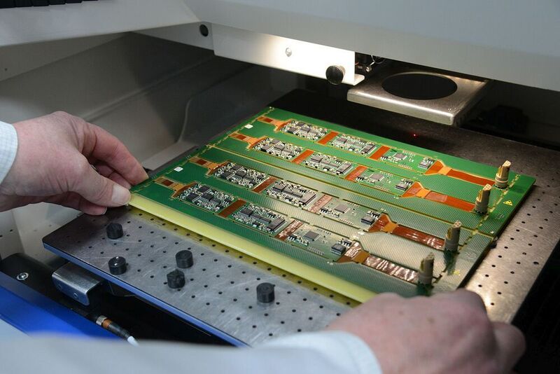Starr-flexible Leiterplatten werden bei ATLAS EMS in die LPKF MicroLine 2000 eingelegt. Da die Baugruppen kompakt und randnah platziert sind und das starr-flexible Material anspruchsvoll in der Bearbeitung ist, erweist sich Trennen mittels Lasertechnologie hier als ideal.  (ATLAS EMS)