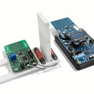 Durchbruch im Labor – IIoT Sensorknoten auf Wiegand-Basis. Links: Die beiden Wiegand-Harvester zwischen den Stabmagneten (unter der weißen Umhausung) und die Sende-Platine mit Mikrocontroller, Temperatursensor und UWB-Sendemodul. Rechts: Die bis zu 60 m entfernte Empfängerstation, welche die Daten per Funknetz einsammelt und als Gateway am Strom angeschlossen ist.(Bild:  Posital)