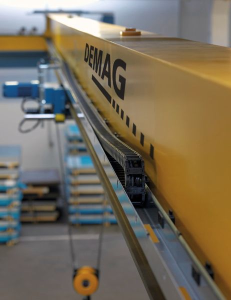 Die Energieführungskette gleitet in einer seitlich am Kranträger montierten Rinne. Diese ist an der Unterseite partiell mit Öffnungen versehen. (Bild: Demag)