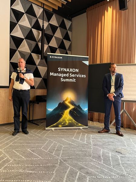 Markus Rex und Jonathan Seifert (Synaxon) begrüßen die Teilnehmenden beim Synaxon Managed Services Summit 2026 in Frankfurt. (Bild: Vogel IT-Medien)