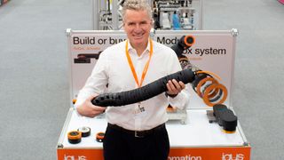 Geschäftsführer Frank Blase ist stolz auf die 168 Neuheiten, die die Igus-Experten vor allem aus dem Homeoffice entwickelt haben. Er zeigt die TRX Roboter-Energiezuführung auf dem  physisch-virtuellen Messestand von Igus in Köln.  (Igus)
