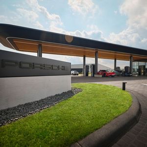 In dem Gewerbegebiet bei Bingen am Autobahndreieck Nahetal (A60/A61) fällt die Porsche Charging Lounge direkt ins Auge. Das abgerundete Dach sieht aus wie eine Flugzeugtragfläche, die von runden Pfeilern gehalten wird. Die Sitzgelegenheiten aus hellem Holz an den Schnellladern sind abgerundet und auch die raumhoch verglaste Lounge hat keine Ecken. (Bild:  Porsche)