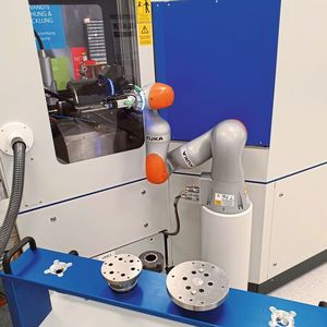 Der Roboterarm holt vorbereitete Werkstücke vom Palettenwagen im Vordergrund und macht den automatischen Werkstückwechsel.