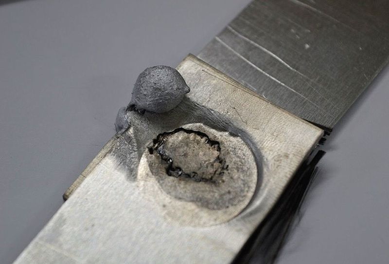 Fünf Lagen des verwendeten Gewebes führten dazu, dass das teilflüssige Aluminium größtenteils in Tropfenform von den Elektroden aus der Fügezone verdrängt, und nur die äußeren Lagen des Carbonaufbaus geringfügig infiltriert wurden. An der Erhöhung der Lagenzahl bei gleichzeitig guter Infiltration mit Aluminium wird derzeit weiter geforscht. (Bild: Marx)