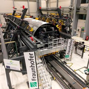 Montage-Forschungsplattform mit eingerüsteten thermoplastischen Rumpfschalen des „MFFD“ bei der Fraunhofer-Gesellschaft in Stade. Gut erkennbar sind die gelben Hexapod-Roboter zum Halten und hochpräzisen Einstellen von Form sowie Lage der Oberschale.(Bild:  Fraunhofer IFAM)