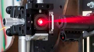 Demonstrationsaufbau einer ultraschnellen Distanzmessung: Der Lauf eines
Luftgewehrs ist fest eingespannt und der beim eigentlichen Versuch unsichtbare
Laserstrahl wird auf die Flugbahn der abgefeuerten Projektile ausgerichtet.  (Bild: Laila Tkotz, KIT)