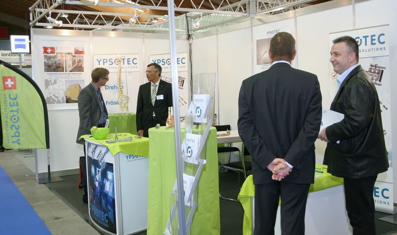 Stand von Ypsotec – auf Medizintechnik spezialiserter Hersteller hochpräziser Dreh- und Frästeile: Geschäftsführer Maurice Meytre (2.v.li.) und Verkaufsleiter Jürg Aegerter (von hinten) im Kundengespräch. (Bild: Anne Richter, SMM)