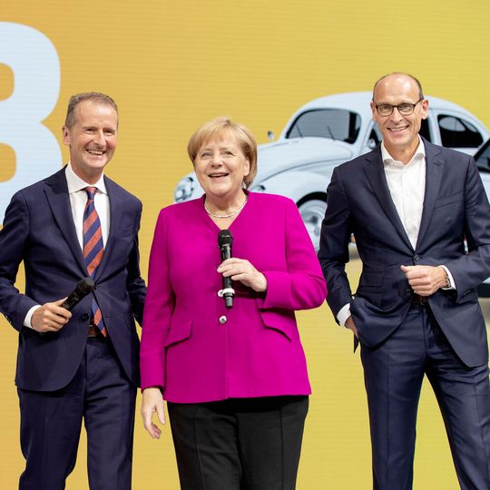 Volkswagen-Chef Herbert Diess (li.) soll sich künftig voll auf seine Aufgaben als Konzernchef konzentrieren. Die Leitung der Marke VW Pkw übernimmt Ralf Brandstätter (re.). Beide umrahmen im Bild Bundeskanzlerin Angela Merkel.(Bild:  Volkswagen)