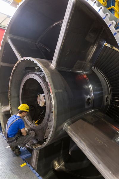 Millimeterarbeit bei der Montage der SGT5-8000H – Im Gasturbinenwerk Berlin wird der so genannte Läufer in das Turbinengehäuse eingelegt. Ein Mitarbeiter beobachtet die Stellung des Läufers beim Einsetzen in den unteren Gehäusestrang. (Siemens)