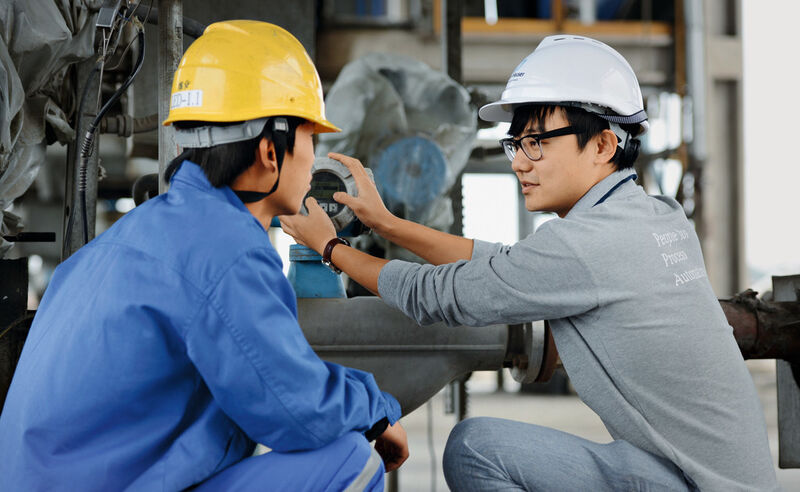 Close to the customer: Project Engineer Song Zhaoming (right) checks a flowmeter with one of the refinery employees. (Picture: Endress+Hauser)