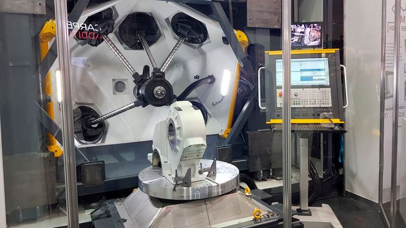 Metrom zeigte gemeinsam mit der Brandenburg Technischen Universität Cottbus (BTU) eine Mobile Reparaturfabrik. Herzstück ist eine Sondermaschine, die auf dem Konzept der Parallelkinematik und einer fünfachsigen Pentapod-Konstruktion basiert. Mittels Direct Energy Deposition (DED) wird je nach Erfordernis ein mit einem Lichtbogen oder Laser aufgeschmolzener Metalldraht lagenweise aufgetragen und so das metallische Bauteil repariert. Für dessen Feinmodellierung erfolgt mit einem anderen Werkzeug die Fräsarbeit in der gleichen Anlage . (Bild: D.Quitter / VCG)