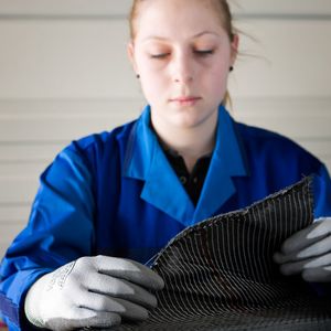 Eine BMW-Mitarbeiterin prüft die Qualität von Carbonfasergewebe.