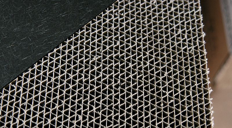 Bild 4: Kofferraumladeböden werden überwiegend als Sandwichkonstruktion gefertigt. Die Decklagen (links oben) bestehen aus Faserverbundkunststoff mit Polyurethanmatrix und der Kern aus Papierwaben. (Bild: Hennecke)