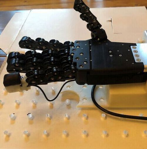 Robotic hand with a 3D-printed tactile fingertip on the little (pinky) finger. The white rigid back to the fingertip is covered with the black flexible 3D-printed skin.