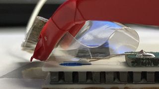 Die biegsame Sensorfolie (transparent) kann die Temperatur einer Wärmeplatte (weiss) messen. In Rot eine kleine Greifzange. (ETH Zürich / Raffaele Di Giacomo)