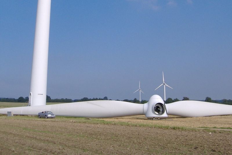 Je höher die Gondel in den Himmel reicht und je größer die sonstigen Dimensionen sind, umso höher kann die Ausbeute der modernen Windmühlen sein. Hier gibt der Vergleich mit dem links stehenden PKW einen Eindruck der Größe zweier Rotorblätter und der Nabe. (Foto: commons.wikimedia.org /KarleHorn (CC BY-SA 3.0))