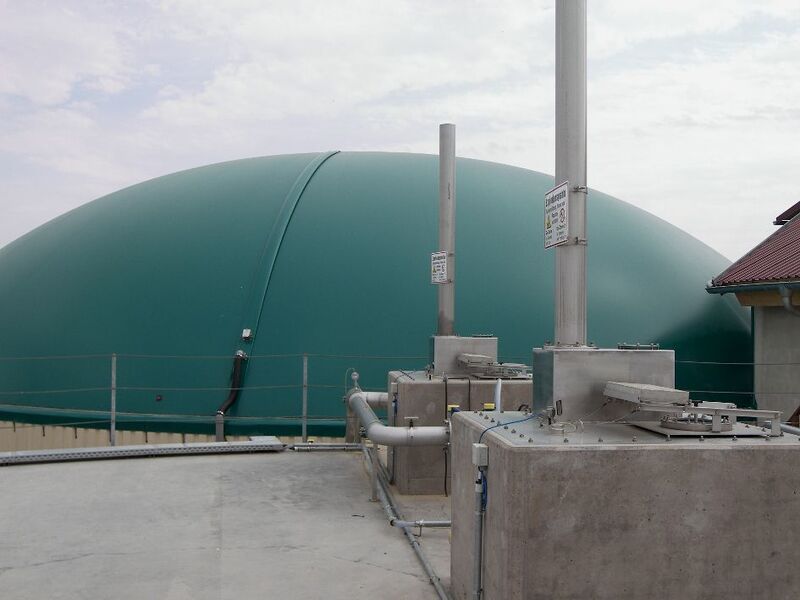 Über dem Fermenter fangen zwei Gasdome das von den Bakterien erzeugte Biogas auf. Nach der Fermentation wird die Biomasse, die sich als geruchsarmer Dünger eignet, in einem Gärrestelager (Hintergrund, mit grüner Kuppel) gespeichert.  (Bild: PROCESS)